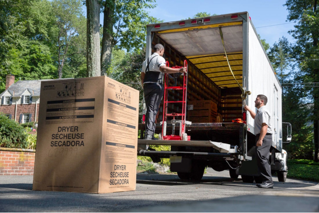 Men unloading box truck with heavy appliances
